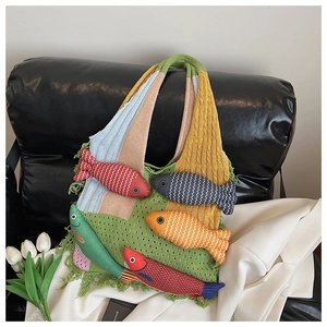 Close-up of knit tote bag with colorful 3D fish appliques and tassel detail on sofa