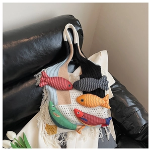 Macro detail of hand-knitted tote bag with 3D fish charms and long fringe tassels
