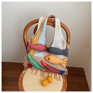 Detail of a handmade knit bucket bag featuring colorful 3D fish charms and fringe trim