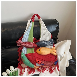 Detail of colorful knitted tote bag featuring artistic 3D fish charms and elegant side tassels