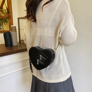 Borsa a tracolla chic a forma di cuore nero con catena e frange indossata da una modella