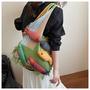 Detail of bohemian knitted tote bag with colorful 3D fish charms on green mesh fabric