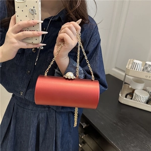 Sac de soirée cylindrique en satin rouge avec chaîne dorée et fermoir perle