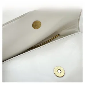 Détail de la fermeture magnétique dorée haut de gamme sur un sac à main en cuir blanc