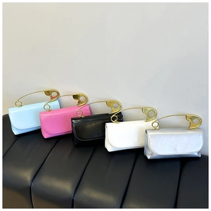 Détail de sacs à bandoulière colorés avec une poignée unique en forme de grande épingle dorée