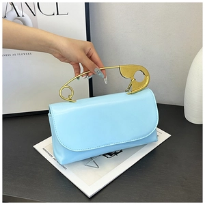 Gros plan du sac en cuir bleu clair avec une poignée unique en épingle à nourrice dorée