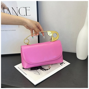 Détail d'un sac à main rose brillant doté d'une poignée dorée en forme d'épingle à nourrice