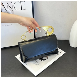 Vue détaillée d'un sac en cuir noir avec une grande poignée en métal doré en épingle