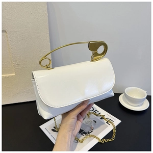 Détail d'un sac à main blanc brillant avec poignée épingle de sûreté dorée et bandoulière