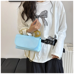 Détail du sac à main bleu clair verni avec poignée en épingle à nourrice dorée et chaîne