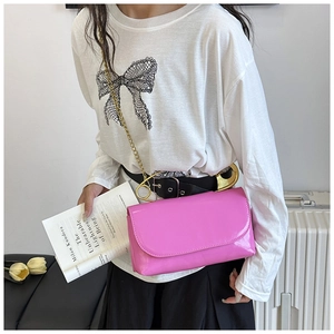 Détail du sac bandoulière rose fuchsia avec épingle de sûreté dorée et bandoulière chaîne