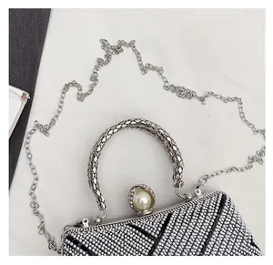 Detail of luxury evening clutch with black white rhinestones, pearl clasp, and metal handle
