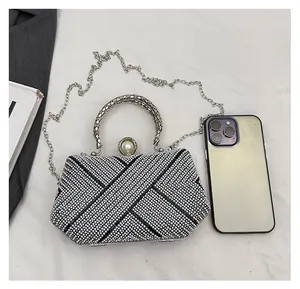 Clutch bag size comparison with a phone featuring silver rhinestones and pearl clasp