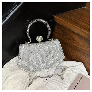 Detailed view of silver rhinestone clutch with pearl clasp and metal ring handle