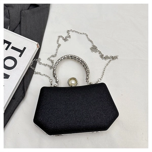 Detail of black glitter evening bag featuring silver woven handle and pearl clasp accent