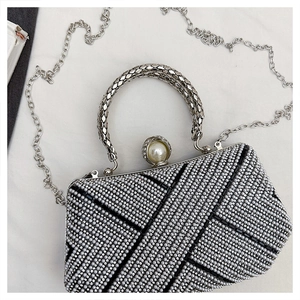 Detail of luxury evening clutch with geometric rhinestones, pearl clasp, and metal handle