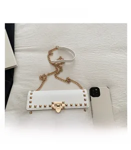 Close-up of white lychee leather saddle bag with golden studs and chain strap