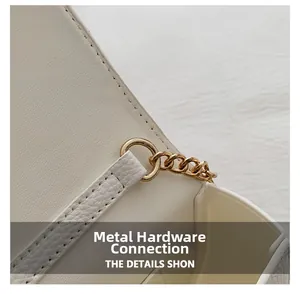 Macro shot of gold metal ring and chain attachment on white pebbled leather bag