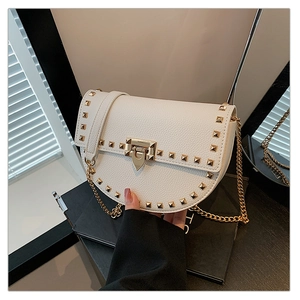 Close-up of beige lychee grain saddle bag with gold square studs and chain strap