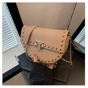 Close-up of beige lychee texture saddle bag featuring gold stud rivets and metal lock