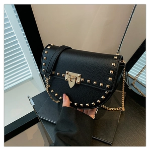 Macro detail of black pebble leather saddle bag featuring golden rockstud studs and lock