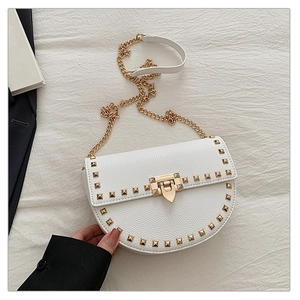 Detail of white saddle bag showing gold rivets and heart-shaped metal clasp texture