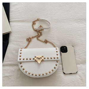 Detail of white saddle bag featuring gold studs, metal clasp, and chain strap