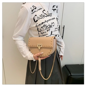Close-up of beige saddle bag with gold square studs and pebbled leather texture
