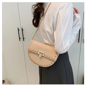 Detail of rivet trim and lychee texture on apricot saddle bag with gold chain strap