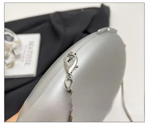 Detailed close-up of high-quality silver lobster clasp and metal chain on luxury acrylic bag