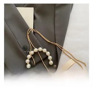 Detail of satin bucket bag with pearl handle and delicate gold snake chain strap
