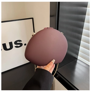 Detail of matte purple oval clutch bag with golden chain strap for evening events