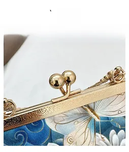 Macro detail of vintage metal clasp with floral engraving on butterfly embroidery bag