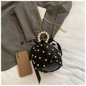 Detail of black satin bucket bag with faux pearls, ribbon bow and pearl ring handle