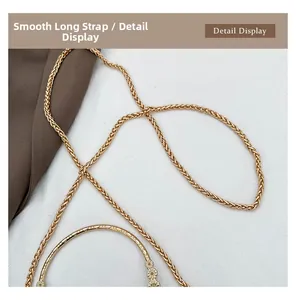 Detail of smooth gold woven chain strap and engraved metal handle on Chinese shell bag