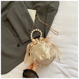 Detail of satin bucket bag featuring pearl embellishments and a gold chain strap