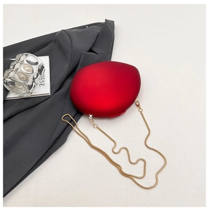 Detail of red matte acrylic clutch with a sleek golden snake chain for formal evening wear