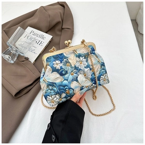 Detail of vintage butterfly embroidery on a shell bag with a gold metal clasp and chain