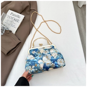 Detailed embroidery of white flowers and golden butterflies on a blue shell-shaped bag