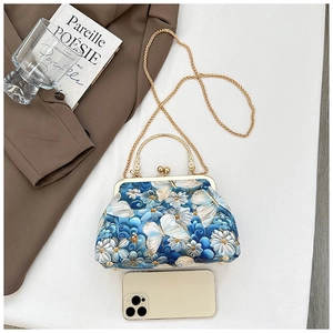Detail of blue butterfly embroidery shell bag with golden metal frame and chain strap