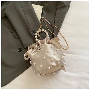 Detailed shot of champagne satin bucket bag with pearl embellishments and chain