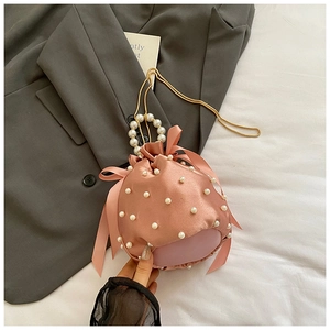 Detailed view of pink satin bucket bag with faux pearls and side decorative bows