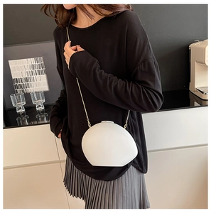 Chic pebble shaped white acrylic crossbody bag with a slim gold chain on a model