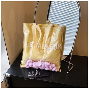 Detail of transparent PVC tote bag with yellow canvas lining and purple duck ornaments
