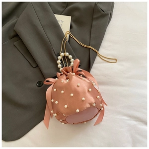 Detailed shot of a pink satin bucket bag featuring pearl handle and silk ribbon bows