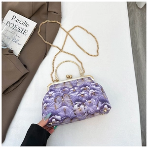 Detail of purple shell bag with butterfly embroidery, gold clasp, and chain strap