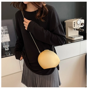 Detailed view of a golden shell-shaped acrylic crossbody bag with a slim chain strap