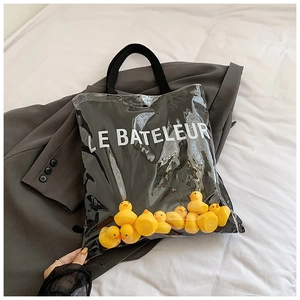 Detail of transparent PVC tote bag with yellow rubber ducks and LE BATELEUR print