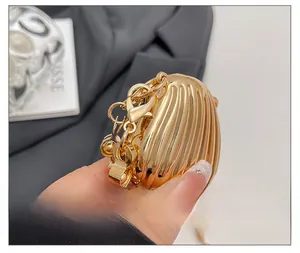 Close-up of golden shell mini bag featuring high-shine metal finish and chain strap