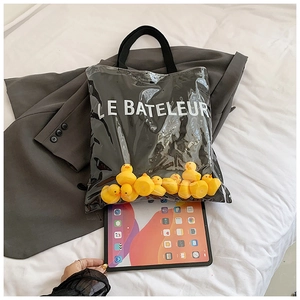 Detail of transparent PVC tote bag featuring black canvas and yellow rubber duck decorations